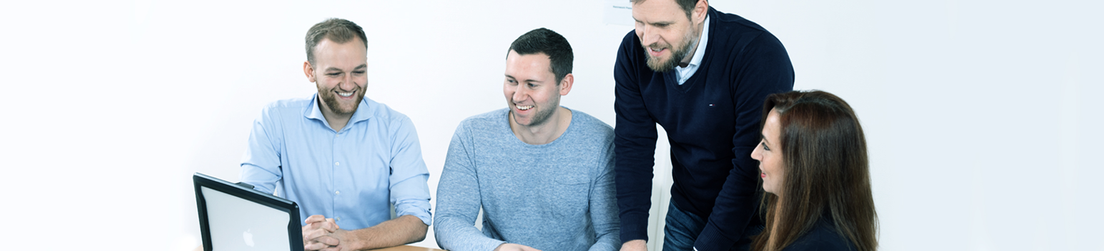 Vier Menschen gucken auf einen Laptop.